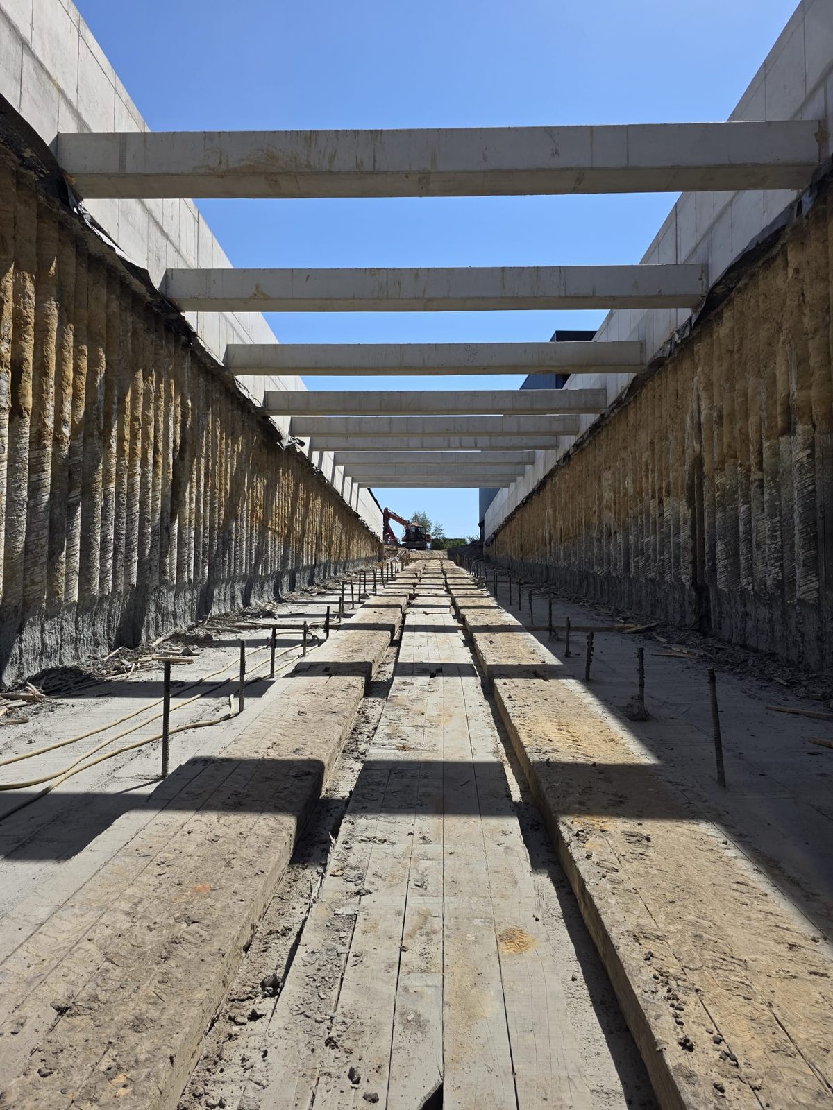 Excavated trench with concrete beams and retaining walls